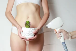 woman in white underwear holding a small potted cactus over her bikini area while a practitioner holds a laser hair removal
